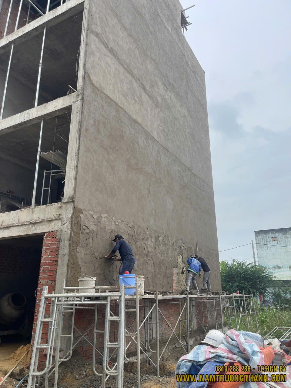 Thợ đang trát tường ngoài nhà phố trong giai đoạn thi công phần hoàn thiện, giúp tạo bề mặt phẳng và chống thấm cho công trình.